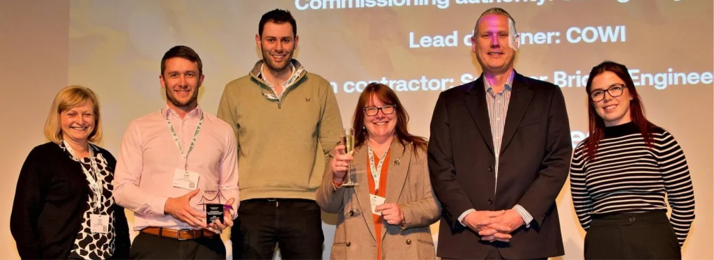 Spencer Group staff stood on stage after receiving award for outstanding refurbishment of a historic bridge