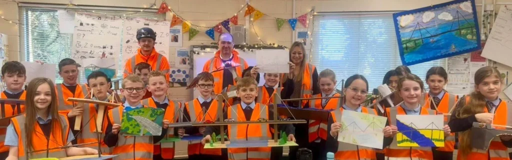 Spencer Bridge Engineering staff surrounded by a class from St Anne’s Primary School in Erskine Scotland holding drawings and models of Erskine Bridge