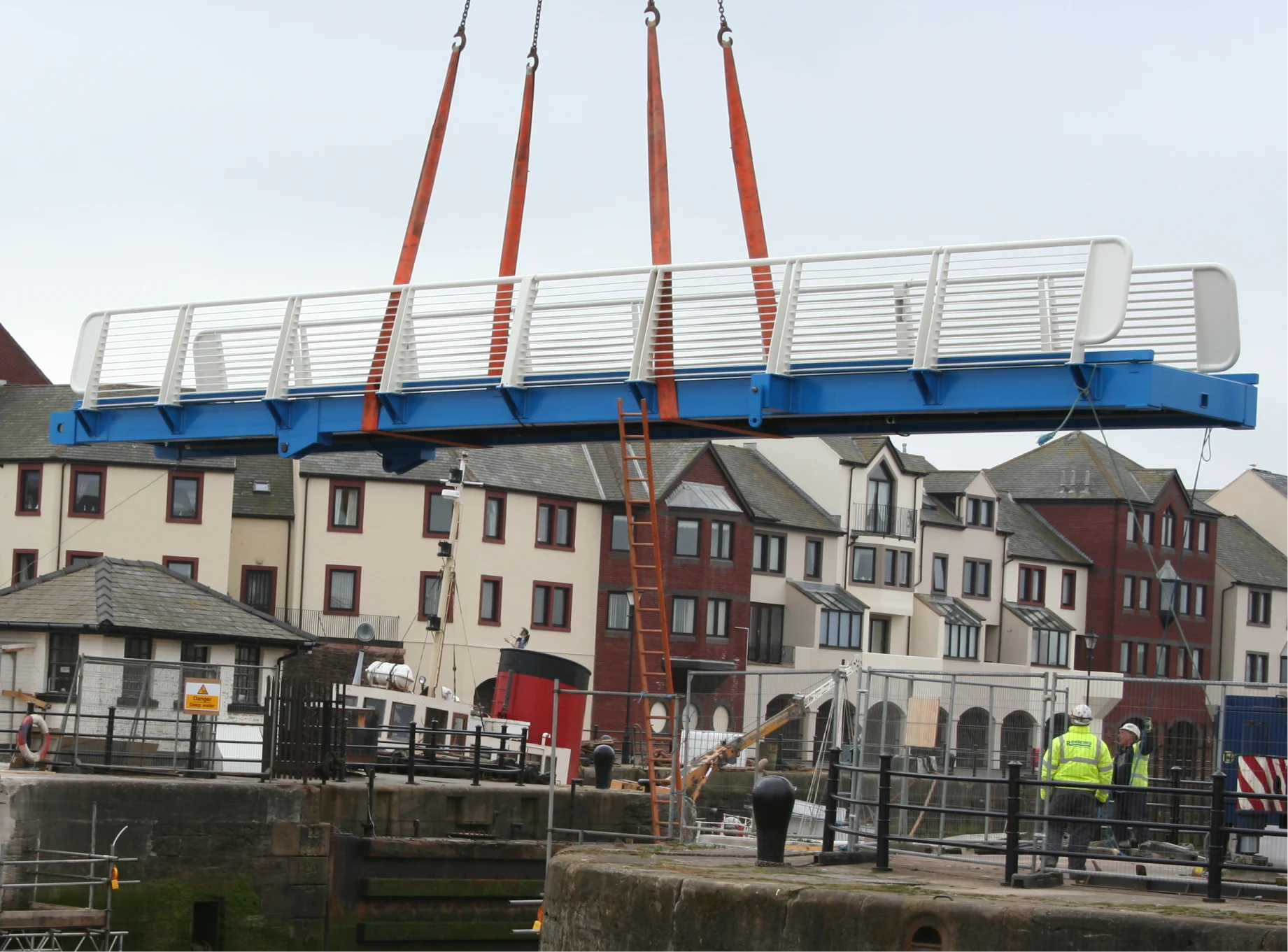 Side-profile of the walkway of the Maryport Articulated Bridge being lifted by a crane